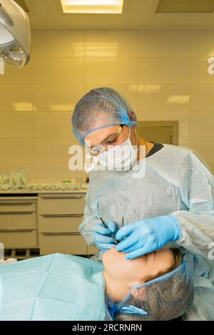 Der Zahnchirurg untersucht den Mund des Patienten, bevor er Weisheitszahn, den Oberkiefer-Drittmolar, entfernt. Echte Prozedur Stockfoto