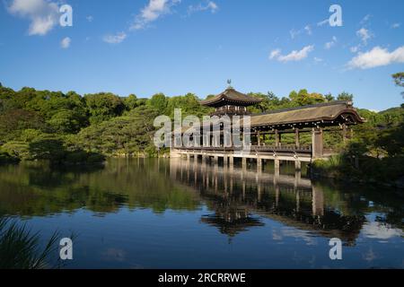 Eine alte, malerische, mit Holz überdachte Brücke in einem japanischen Garten in Heian Jingu, die man in Kyoto, Japan, während einer Luxusreise als Tour gesehen hat Stockfoto