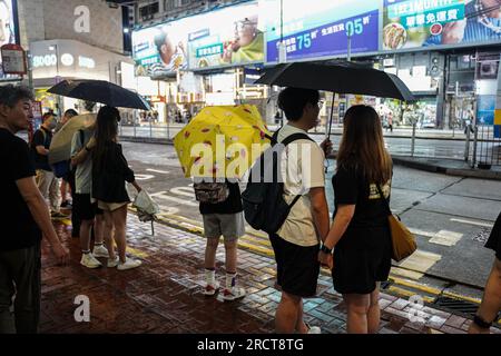 Hongkong, China. 16. Juli 2023. Die Leute laufen mit Sonnenschirmen auf der Straße. Am 16. Und 17. Juli bereitete sich Hongkong auf die Ankunft des Taifuns Talim vor, da die Stadt das T8-Warnsignal vom Hong Kong Observatory zum ersten Mal im Jahr 2023 ausgab. Wenn sich der Sturm nähert, spüren Sie die Auswirkungen in verschiedenen Teilen der Stadt, einschließlich Tsim Sha Tsui und Heng Fa Chuen, wo die Bewohner die Macht des Taifuns erleben. Kredit: SOPA Images Limited/Alamy Live News Stockfoto