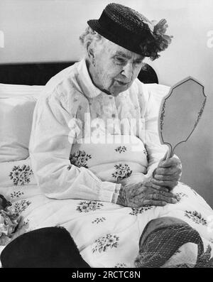 San Francisco, Kalifornien: ca. 1962 eine ältere Frau, die im Bett sitzt, sieht sich in einem Spiegel an. Stockfoto