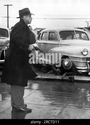 Los Angeles, Kalifornien: 1. Oktober 1946. Ein Deputy Sheriff steht mit einer schiefen Pistole neben einem gefallenen Offizier und hält eine Menge Streikposten zurück, die im MGM Studio demonstrieren. Stockfoto