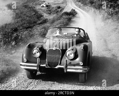 USA: 1958 Ein Paar fährt mit einem Jaguar XK 150-Coupé mit 1958-mm-Abzweigkanal durch das Land Stockfoto