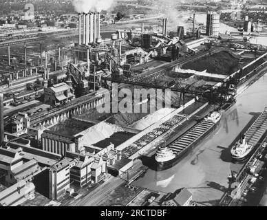 Dearborn, Michigan: Mai 1947, Werk River Rouge der Ford Motor Company, in dem im Hintergrund Eisenerz, Kohle und Kalkstein zur Versorgung der Hochöfen, der Gießerei und des Kraftwerks gelagert werden. Zwei Eisenerzträger befinden sich am Dock rechts. Stockfoto