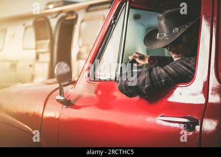 Ein weißer Cowboy mittleren Alters in einem klassischen Pickup Truck neben seinem Reiseanhänger Stockfoto