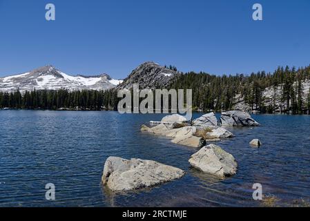 Aloha-See mit Felsbrocken im blauen Wasser und umgeben die schneebedeckten Alpenberge. Stockfoto