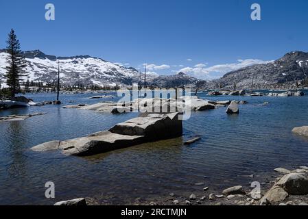 Aloha-See mit Felsbrocken im blauen Wasser und umgeben die schneebedeckten Alpenberge. Stockfoto