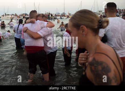 Malaga, Spanien. 16. Juli 2023. Zwei Brüder von 'Virgen del Carmen' sehen sich am Strand umschließen, nachdem die Prozession im Viertel 'El Palo' beendet wurde. Jedes Jahr, am 16. Juli, feiert Malaga ein religiöses Fest zu Ehren der „Virgen del Carmen“, Schutzpatron der Seeleute und Fischer. Die Statue der Jungfrau, getragen von einer Gruppe von Gläubigen in traditionellen Kostümen entlang der Straßen, wird auf einem Boot vom Strand platziert, das später die Küste Malagas hinunter segelt. Kredit: SOPA Images Limited/Alamy Live News Stockfoto