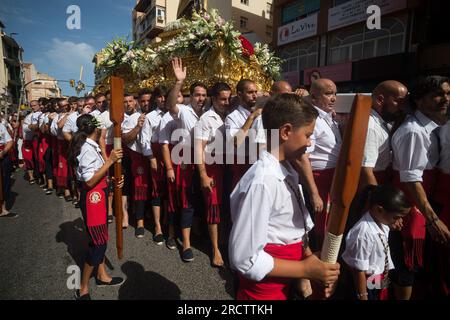 Malaga, Spanien. 16. Juli 2023. Die Brüder „Virgen del Carmen“, die an einer Prozession im Viertel „El Palo“ teilnehmen, tragen die Statue der Jungfrau. Jedes Jahr, am 16. Juli, feiert Malaga ein religiöses Fest zu Ehren der „Virgen del Carmen“, Schutzpatron der Seeleute und Fischer. Die Statue der Jungfrau, getragen von einer Gruppe von Gläubigen in traditionellen Kostümen entlang der Straßen, wird auf einem Boot vom Strand platziert, das später die Küste Malagas hinunter segelt. Kredit: SOPA Images Limited/Alamy Live News Stockfoto