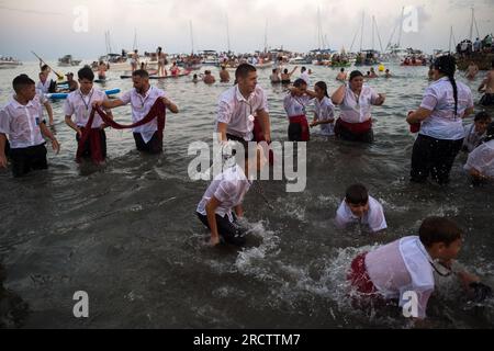 Malaga, Spanien. 16. Juli 2023. Die Brüder Virgen del Carmen werden am Strand beim Spielen mit dem Wasser gesehen, nachdem die Prozession im Viertel El Palo beendet wurde. Jedes Jahr, am 16. Juli, feiert Malaga ein religiöses Fest zu Ehren der „Virgen del Carmen“, Schutzpatron der Seeleute und Fischer. Die Statue der Jungfrau, getragen von einer Gruppe von Gläubigen in traditionellen Kostümen entlang der Straßen, wird auf einem Boot vom Strand platziert, das später die Küste Malagas hinunter segelt. Kredit: SOPA Images Limited/Alamy Live News Stockfoto