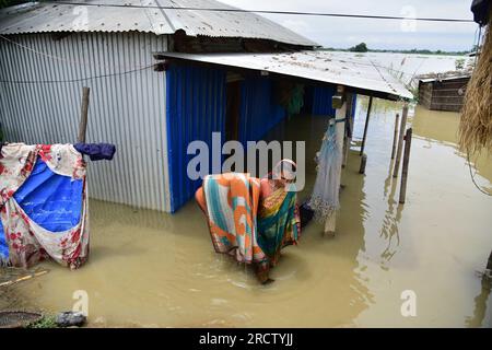 Morigaon. 16. Juli 2023. Eine Frau verlegt ihre Habseligkeiten außerhalb ihres wasserdurchlässigen Slums in einem von der Flut betroffenen Gebiet im Morigaon-Bezirk im nordöstlichen Bundesstaat Assam, 16. Juli 2023. Kredit: Str/Xinhua/Alamy Live News Stockfoto