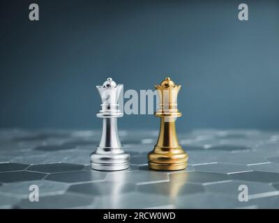 Goldene und silberne Queen-Luxusschachfiguren, die auf einem silbernen sechseckigen Schachbrett auf blauem Hintergrund stehen. Anführer, Freund, Feind, cooper Stockfoto