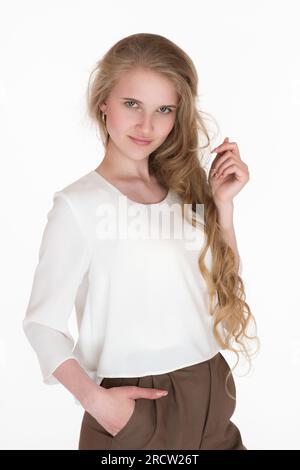 Porträt einer charismatischen jungen Frau, die in die Kamera starrt. Gut gekleidete blonde Weiße, 21 Jahre alt, mit langen Haaren und weißer Bluse Stockfoto