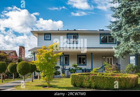 Durchschnittliches nordamerikanisches Familienhaus an einem sonnigen Tag. Familienhaus. Wohnfamilienhaus mit Betonpfad über grünen Rasen im Vorgarten. Betreff Stockfoto