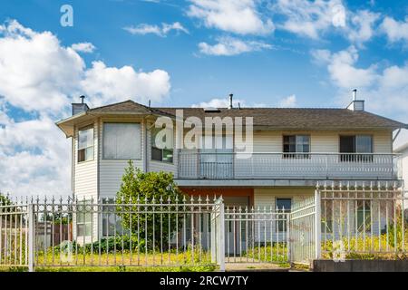 Durchschnittliches nordamerikanisches Familienhaus an einem sonnigen Tag. Familienhaus. Wohnfamilienhaus mit Betonpfad über grünen Rasen im Vorgarten. Betreff Stockfoto