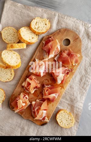 Scheiben von appetitanregenden Jamon Serrano bereit zum Essen auf einem rustikalen Holzbrett, Blick von oben. Flach liegend, über Kopf, von oben. Stockfoto