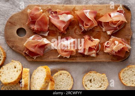 Scheiben von appetitanregenden Jamon Serrano bereit zum Essen auf einem rustikalen Holzbrett, Blick von oben. Flach liegend, über Kopf, von oben. Stockfoto