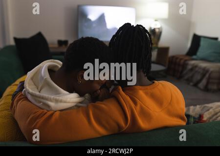 Ein afroamerikanisches Paar, das sich zu Hause entspannt, verängstigt ist, sich umarmt, sich einen gruseligen Film ansieht Stockfoto