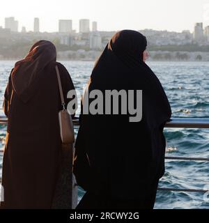 Zwei muslimische Frauen genießen den Sonnenuntergang über dem Bosporus von Uskudar auf der asiatischen Seite von Istanbul, Türkei Stockfoto