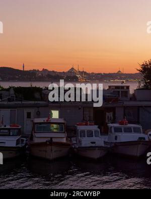 Boote liegen bei Sonnenuntergang in Uskudar auf der asiatischen Seite von Istanbul, Türkei. Westseite der Stadt und Moschee im Hintergrund. Stockfoto