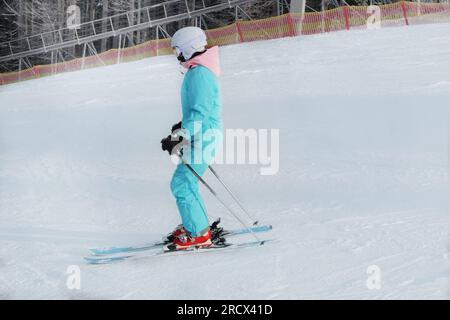 Skifahrer in blauem Skianzug steigt auf dem Lift die Berghänge hinauf. Skisport im Winter. Urlaub in den Bergen im Skigebiet. Stockfoto