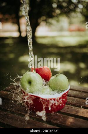 Äpfel in einer Schüssel unter fließendem Wasser. Stockfoto