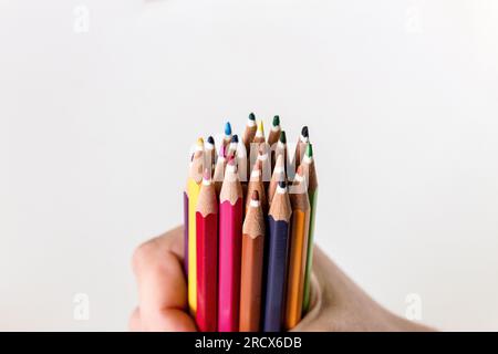 Mehrfarbige Bleistifte. Farbbleistift-Set zum Halten von Händen. Nahaufnahme und Kopierbereich. Ideen und Konzepte. Stockfoto