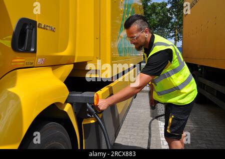 Berlin, Deutschland. 13. Juli 2023. Die Deutsche Post DHL hat 13 große Elektrofahrzeuge für den Transport von Paketen zwischen Vertriebszentren gekauft. Auf diesem Foto vom 13. Juli 2023 verbindet ein Postangestellter ein Fahrzeug mit einem Ladegerät. Kredit: Zapotocky Ales/CTK Photo/Alamy Live News Stockfoto