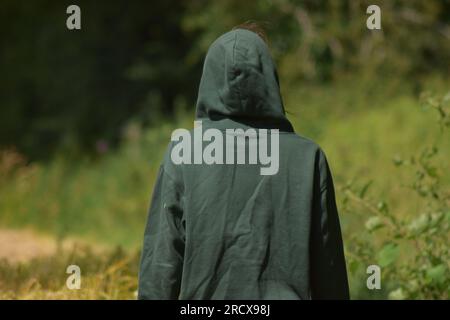 Bilder von Menschen in Kapuzenpullover, die durch Felder und unter einer schmalen Brücke laufen. Stockfoto