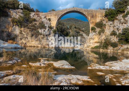 Blick auf eine alte Brücke Pont de Llierca in Katalonien, Spanien. Diese schöne Brücke, gepflastert mit Sandsteinplatten, ist seit dem 14.. Jahrhundert in Gebrauch. Stockfoto