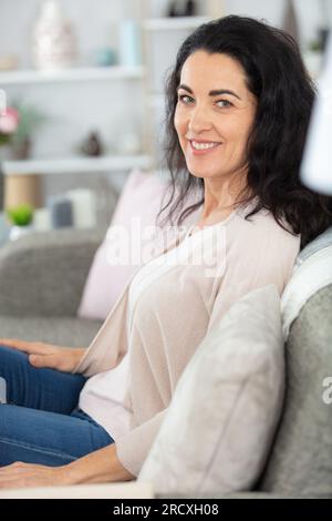 Legerer Anzug, Frau mittleren Alters, die auf dem Sofa sitzt Stockfoto