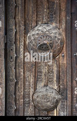 Eine dekorierte Holztür mit Eisengriff an einem Haus in der Altstadt von Jajce. Zentralbosnisch-Herzegowina, Balkanhalbinsel, Osteuropa. Stockfoto