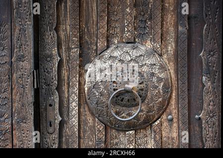 Eine dekorierte Holztür mit Eisengriff an einem Haus in der Altstadt von Jajce. Zentralbosnisch-Herzegowina, Balkanhalbinsel, Osteuropa. Stockfoto