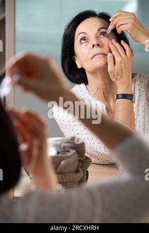 Seniorin, die zu Hause Augentropfen macht Stockfoto