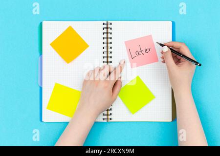 Die Frau schrieb das Wort spät auf eine schriftliche Erinnerung in einem Notizblock. Stockfoto