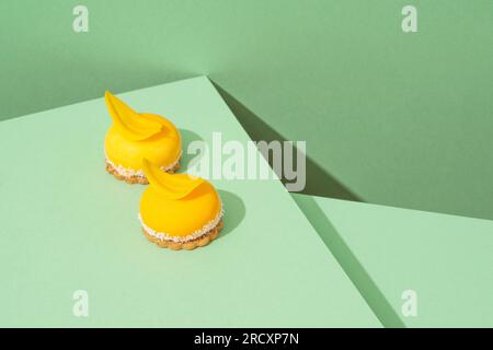 Ein Tablett mit frisch gebackenen gelben Cupcakes mit köstlichem weißem Schlagseißguss auf grünem Hintergrund Stockfoto