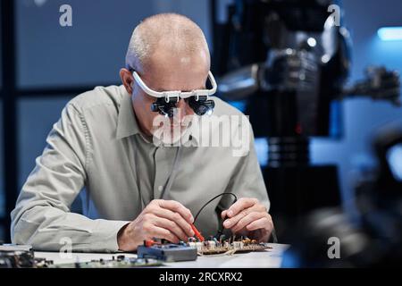 Reifer Entwickler in Spezialgläsern für das Löten von Hauptplatinen am Tisch im Labor Stockfoto