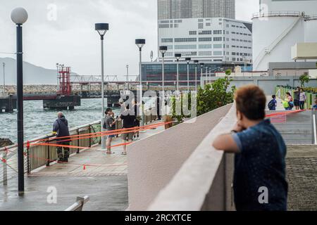 Die Leute wagen sich raus und spüren die Macht des Taifuns Talim in Heng Fa Chuen. In den frühen Stunden des 17. Juli, als sich der Taifun Talim Hongkong nähert, gibt das Hong Kong Observatory um 12:40 Uhr morgens das Warnsignal für den Taifun Nr. 8 aus Dieses Signal ruft in der ganzen Stadt erhebliche Veränderungen hervor, wobei die meisten Busverbindungen zum Stillstand kommen und die Börse als Reaktion auf die unmittelbare Gefahr ihre Türen schließt. Inmitten dieser Vorsichtsmaßnahmen bietet die MTR (Mass Transit Railway) jedoch weiterhin begrenzte U-Bahn-Dienste an, um sicherzustellen, dass Anwohner und Reisende über ein Transportmittel verfügen Stockfoto