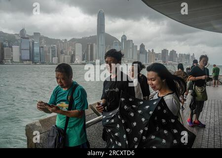 Die Menschen wagen sich zum Kowloon Public Pier in Tsim Sha Tsui und spüren die Macht des Taifuns Talim während des No.8 Warnsignals. In den frühen Stunden des 17. Juli, als sich der Taifun Talim Hongkong nähert, gibt das Hong Kong Observatory um 12:40 Uhr morgens das Warnsignal für den Taifun Nr. 8 aus Dieses Signal ruft in der ganzen Stadt erhebliche Veränderungen hervor, wobei die meisten Busverbindungen zum Stillstand kommen und die Börse als Reaktion auf die unmittelbare Gefahr ihre Türen schließt. Inmitten dieser Vorsichtsmaßnahmen bietet die MTR (Mass Transit Railway) jedoch weiterhin nur begrenzte U-Bahn-Dienste an, um sicherzustellen, dass sie sich dort aufhalten Stockfoto