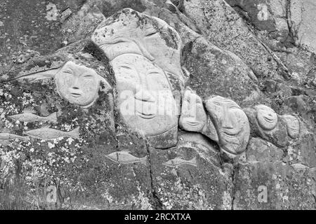 Faces, Rock Art Carvings, Teil des Stone & man-Projekts des lokalen Künstlers alias Høegh auf Qaqortoq, Grönland im Juli - monochrom, schwarz und weiß Stockfoto