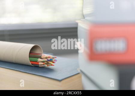 Schulbedarf auf Holztisch in warmer Inneneinrichtung, Schulbücher auf Tisch, Bildungskonzept. Stockfoto