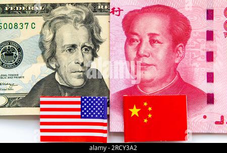 Ein 20-Dollar-Schein und ein chinesischer 100-Yuan-Schein, wobei die US-amerikanischen und chinesischen Nationalflaggen in Weiß isoliert sind. Internationale Finanz- und Handelskonkurrenz CO Stockfoto