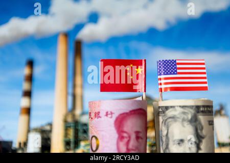 Eine Rolle US-Dollar mit amerikanischer Flagge und ein Bündel chinesischer Yuan und chinesischer Nationalflagge mit industriellem Hintergrund. Ein internationaler Handel Stockfoto