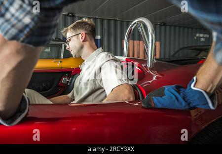 Ein Weißer Fahrzeugbesitzer Testet Sein Klassisches Muscle Car, Während Sein Automechaniker Zusieht Stockfoto
