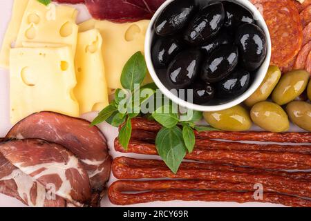 Nahaufnahme einer Vorspeise aus Oliven und Oliven, Basilikum und Käse, dünnen Würsten und Schweinekragen. Draufsicht. Stockfoto
