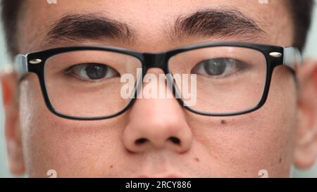 Nahaufnahme eines fokussierten asiatischen Geschäftsmanns, trägt eine Brille, um die Belastung der Augen zu reduzieren Stockfoto