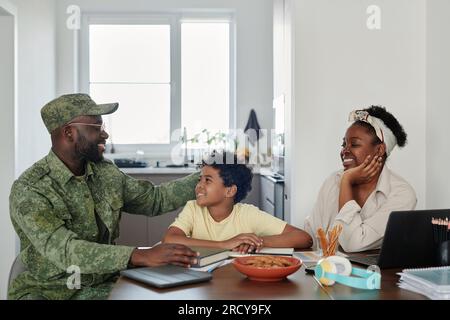 Die Familie freute sich, ihren Vater aus dem Krieg zurückkommen zu sehen, sie saßen am Tisch in der Küche und unterhielten sich miteinander Stockfoto