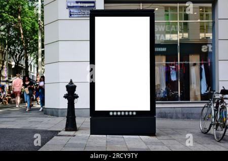 Leere weiße Anzeige und Werbetafel. Modellbasis. Leerer Posterhintergrund. Weicher urbaner grüner Hintergrund. Anzeigenbereich im vertikalen Format. Stockfoto