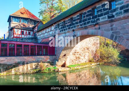 Brückenbogenbrücke über den Fluss im Herbst. Alte Fachwerkhäuser am Ufer des Flusses Pegnitz, Deutschland Stockfoto