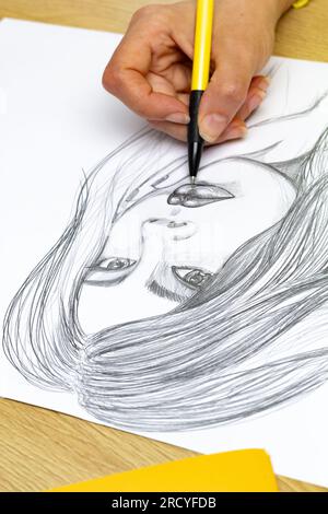 Der Künstler zeichnet ein Porträt einer Frau mit einem Bleistift auf weißem Papier. Stockfoto