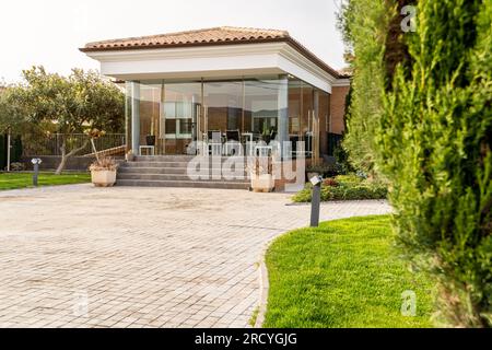 Vorderansicht eines privaten Hauseingangs mit Veranda und Garten mit Bäumen Stockfoto